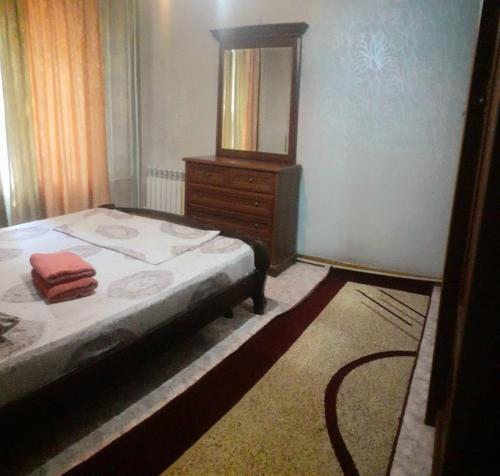 a bedroom with a bed and a dresser with a mirror at Иляева 66 парк Кен Баба in Shymkent
