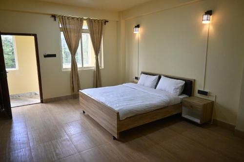 sypialnia z łóżkiem z białą pościelą i oknem w obiekcie TreeTops Residency w mieście Shillong