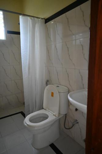 uma casa de banho com um WC branco e um lavatório. em TreeTops Residency em Shillong