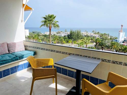 einen Tisch und Stühle auf einem Balkon mit Meerblick in der Unterkunft MEERBLICK BEACH-APARTMENT Monte Rojo in San Agustín