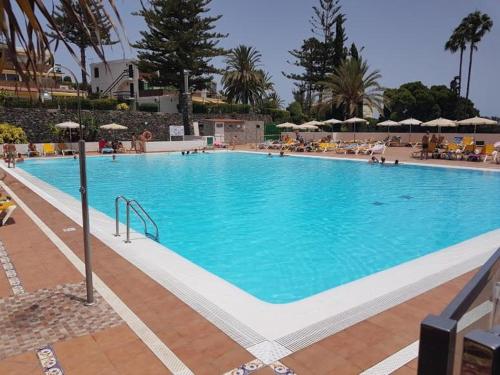 ein großer blauer Pool mit Leuten um ihn herum in der Unterkunft MEERBLICK BEACH-APARTMENT Monte Rojo in San Agustín