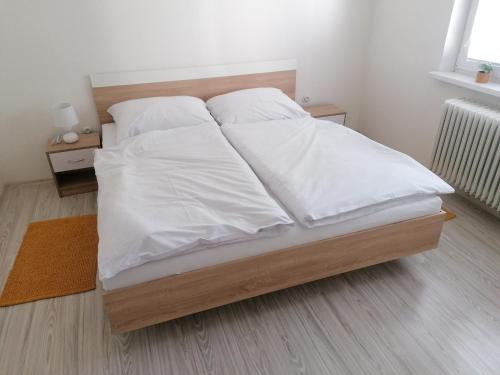 - un lit avec des draps et des oreillers blancs dans l'établissement Apartmán RUŽA14, à Ružomberok