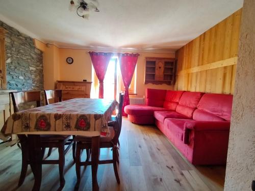salon z czerwoną kanapą i stołem w obiekcie Au Coeur de Saint Nicolas w mieście Saint-Nicolas