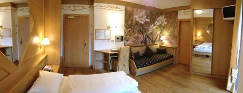 a bedroom with a bed and a desk in a room at Hotel La Serenella in Moena