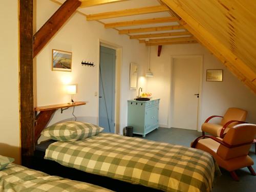 a bedroom with two beds and a chair at de Dars in Callantsoog