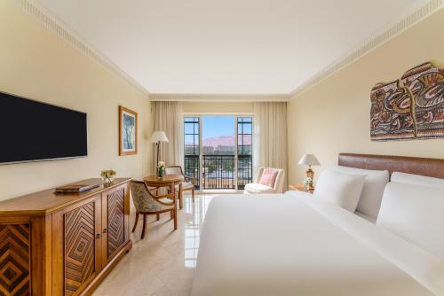 una habitación de hotel con una cama y un televisor en Mövenpick Resort & Residences Aqaba, en Áqaba