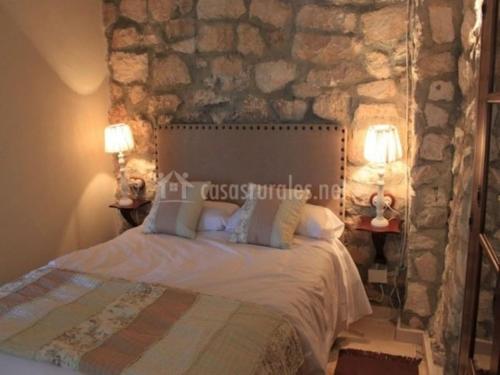 Cama en habitación con pared de piedra en El BALCÓN de los OLIVOS en Luque