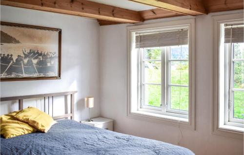 a bedroom with a blue bed and two windows at Gorgeous Home In Vallavik With House Sea View in Kaland