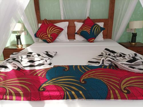 a bedroom with two beds with colorful blankets and pillows at Zanzicrown in Nungwi