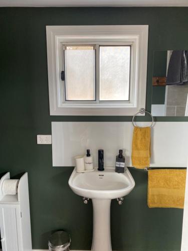 baño con lavabo blanco y ventana en Tiny Home on a Hill en Heathcote