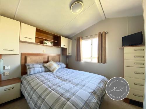 a small bedroom with a bed and a window at Coral Beach - Ingoldmells - Row 89 Van 1 in Ingoldmells