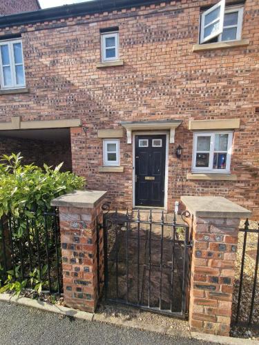 une maison en briques avec une porte noire devant elle dans l'établissement Sunny House, à Haydock