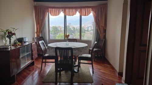 comedor con mesa, sillas y ventana en Apartamento, cómodo, en el corazón de Cochabamba en Cochabamba