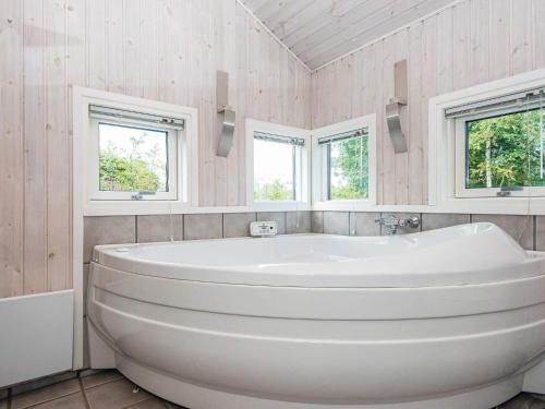 La salle de bains est pourvue d'une baignoire blanche et de 2 fenêtres. dans l'établissement 8 person holiday home in Ebeltoft, à Ebeltoft