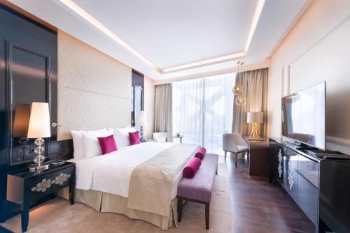 a bedroom with a large bed and a television at Shaza Doha in Doha