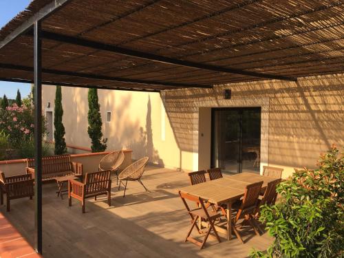 un patio con una mesa de madera y sillas en una terraza en Location de gîte - Mas catalan (66), en Camélas