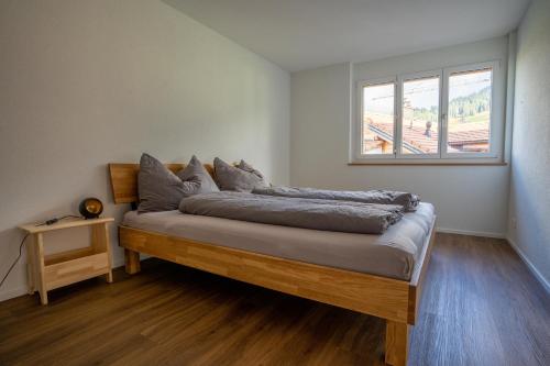 a bed in a room with a window at Chuenislodge1 Neu, grosse Terrasse & Designerofen, prächtige Aussicht in Adelboden