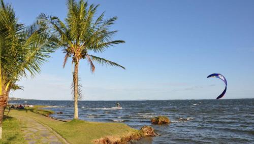 a kite is flying over the ocean with palm trees at Casa em Condomínio com Piscina Privativa in Araruama