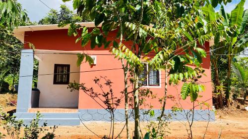 una piccola casa rossa e bianca con un albero di Misty Mud House a Idukki