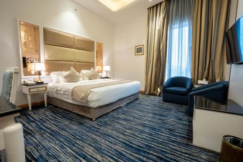 a hotel room with a bed and a chair at Platinum Al Khamseen Serviced Apartments in Taif
