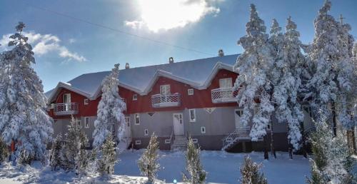 a red house with snow covered trees in front of it at Enigma Apartmani Divcibare in Divčibare