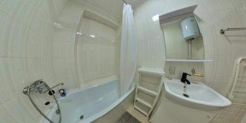 uma casa de banho branca com uma banheira, um lavatório e um WC. em Casa de Raduga West em Koshkolʼ