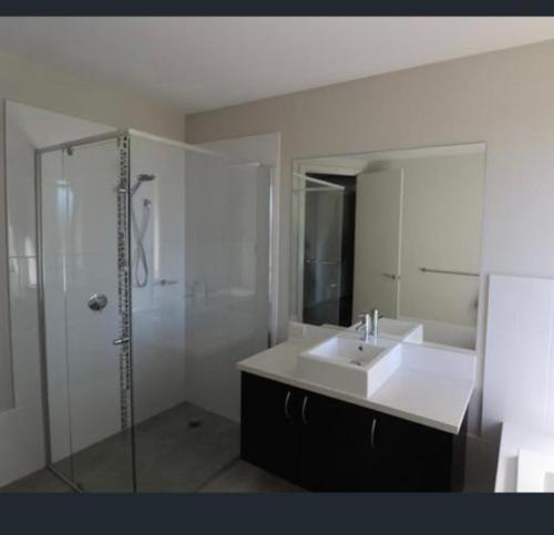 a white bathroom with a sink and a shower at Gibbagunyah Manor Workers Accommodation Only in Muswellbrook