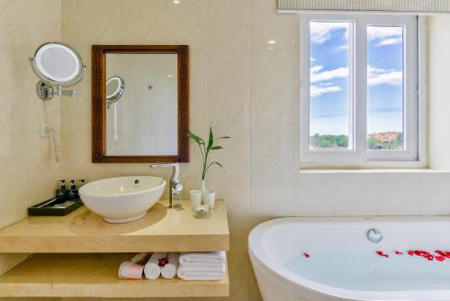 a bathroom with a tub and a sink and a mirror at River Suites Hoi An in Hoi An