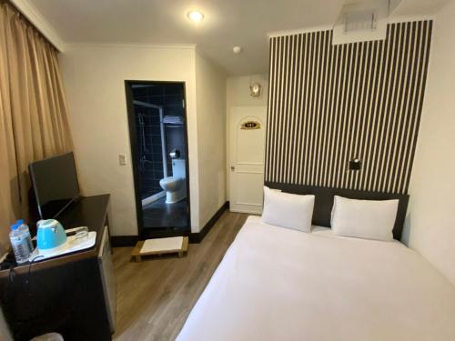 a bedroom with a bed and a bathroom with a toilet at Queens Hotel in Taipei