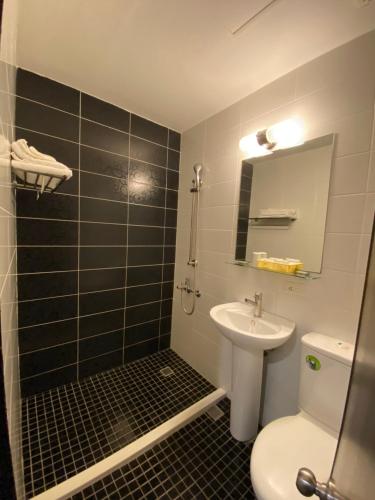 a bathroom with a sink and a toilet and a mirror at Queens Hotel in Taipei