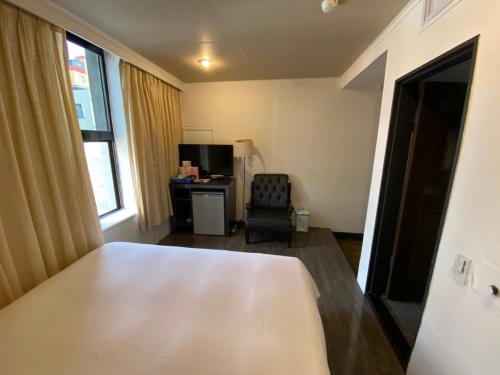 um quarto com uma cama, uma secretária e uma cadeira em Queens Hotel em Taipei