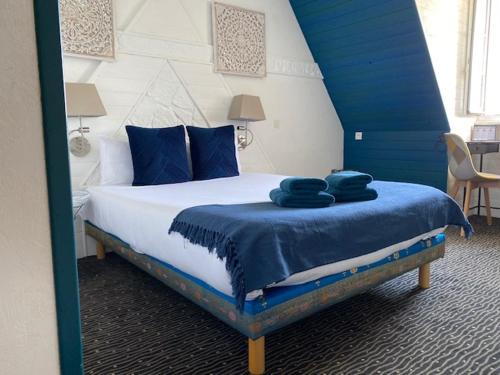 a bedroom with a bed with blue pillows on it at Hôtel Bien-Être Aux Cyprès de Marquay in Marquay