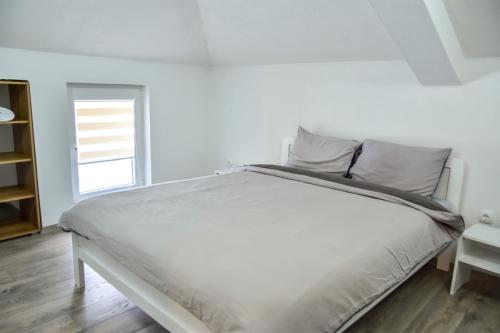 een wit bed in een witte kamer met een raam bij Papi Apartments in Kruševo