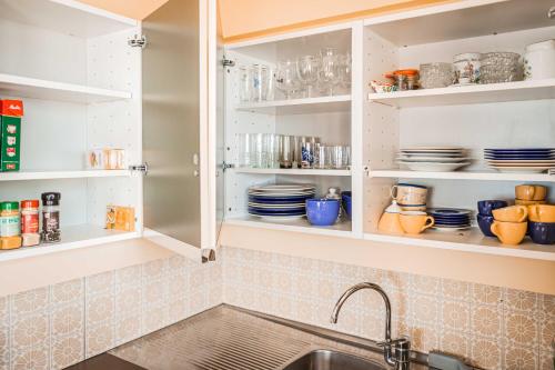 a kitchen with a sink and shelves with dishes at Uniek zeezicht Oostende in Ostend