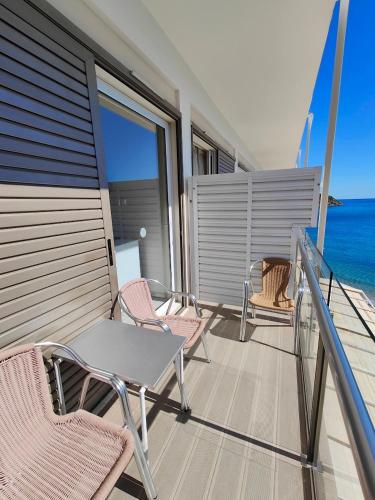 a table and chairs on a balcony with the ocean at New Aegli Resort Hotel in Poros
