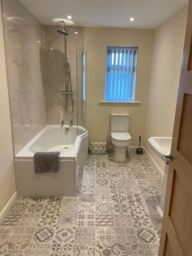 La salle de bains est pourvue d'une baignoire, de toilettes et d'une douche. dans l'établissement The Poplars, à Bridlington