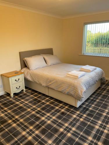 a bedroom with a bed with a night stand and a window at The Poplars in Bridlington