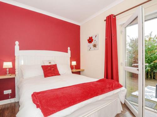 a red bedroom with a white bed and a window at The Station Masters Lodge in Hayle