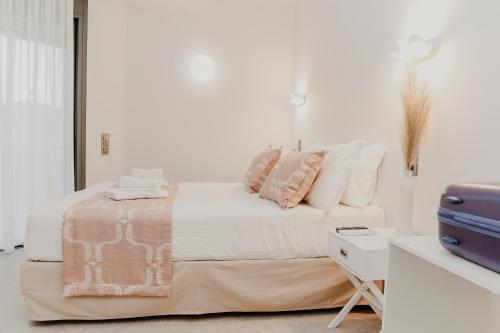 een witte slaapkamer met een bed met roze en witte kussens bij Quattro Luxury Apartments in Tríkala