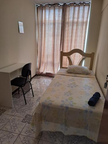 a bedroom with a bed and a desk and a window at Pousada do Luquinhas in Brasilia