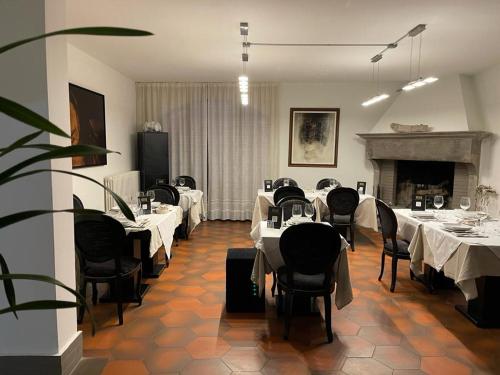 uma sala de jantar com mesas e cadeiras brancas e uma lareira em Agriturismo Villa Paradiso Esotico em Città di Castello