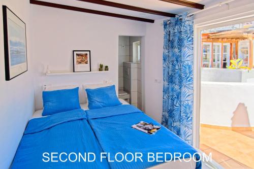 een slaapkamer met een blauw bed in een kamer bij The Palm House in Puerto de Mogán