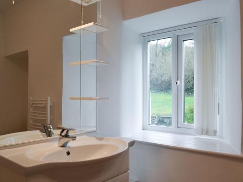 La salle de bains blanche est pourvue d'un lavabo et d'une fenêtre. dans l'établissement Riverside Cottage, à High Nibthwaite