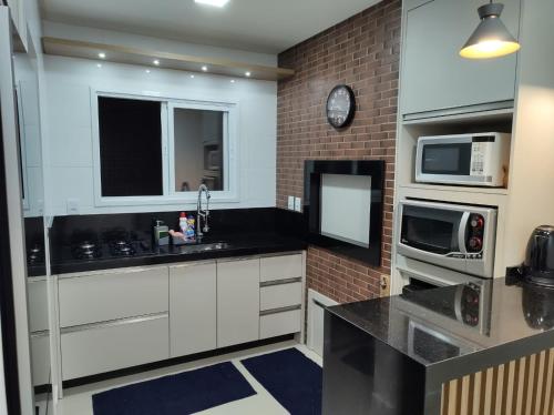 a kitchen with white cabinets and a brick wall at Condado Da Praça in Capão da Canoa