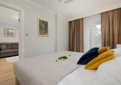 sypialnia z dużym białym łóżkiem z żółtymi poduszkami w obiekcie Baltic Residence Apartamenty Alkam apartament nr 7, 8 - Klimatyzowany, Warszawska 11 w Pobierowie