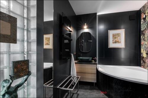ein schwarzes Bad mit einer Badewanne und einem Waschbecken in der Unterkunft P&O Apartments Bitwy Warszawskiej - Ochota in Warschau