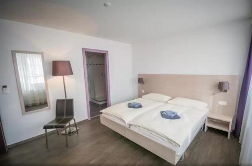 a bedroom with a large white bed and a chair at Hôtel de ville du Sentier in Le Sentier