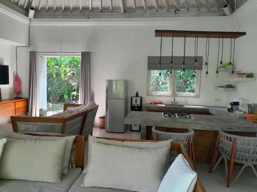 a living room with a couch and a kitchen with a table at Balian Bliss Retreat Bungalow & Villas in Balian