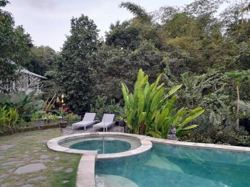 a patio with two chairs and a swimming pool at Balian Bliss Retreat Bungalow & Villas in Balian