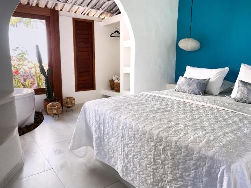 a bedroom with a white bed and a blue wall at Pousada Ilha do Vento in São Miguel do Gostoso